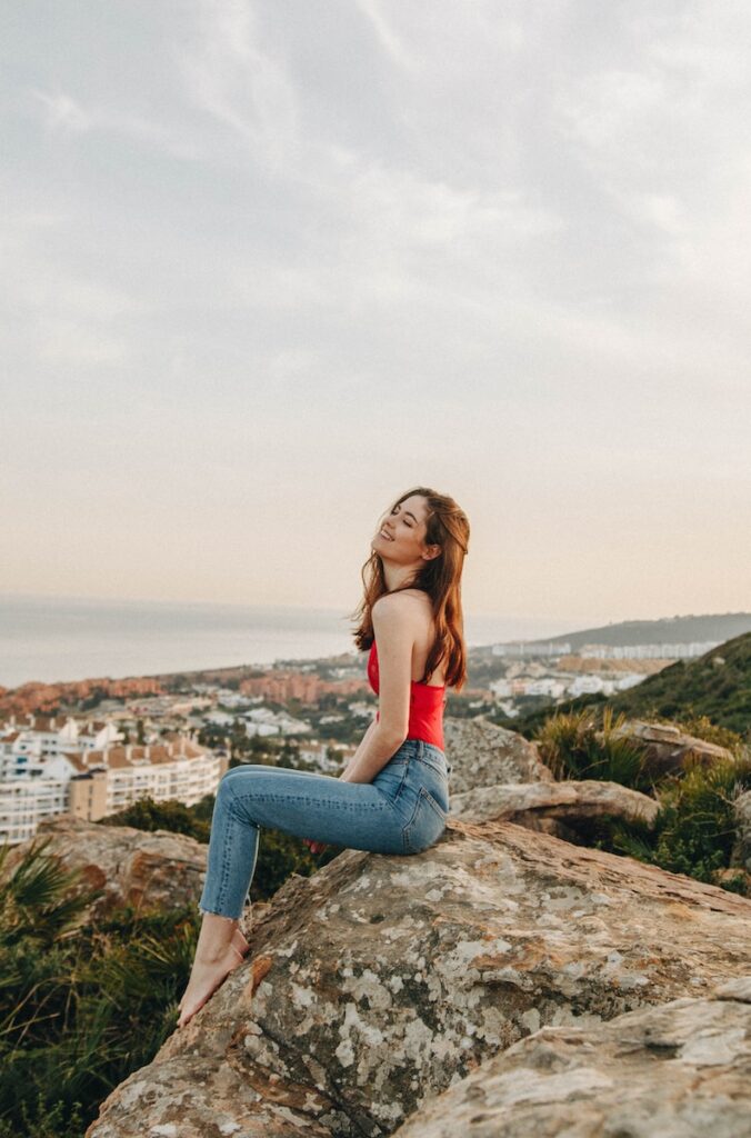 woman sitting on rock using cbd oil